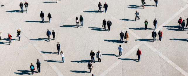 Aerial view of people walking in pairs or alone in concreted public square.