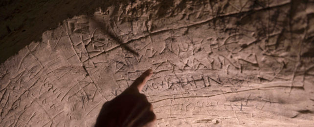 Finger pointing at inscriptions carved in wall of the Tomb of Salome in Israel.