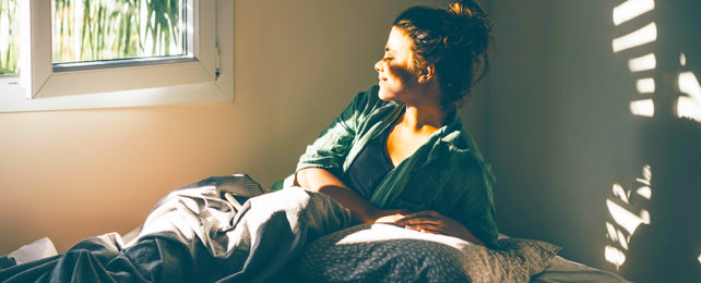 woman waking in bed with a smile on her face